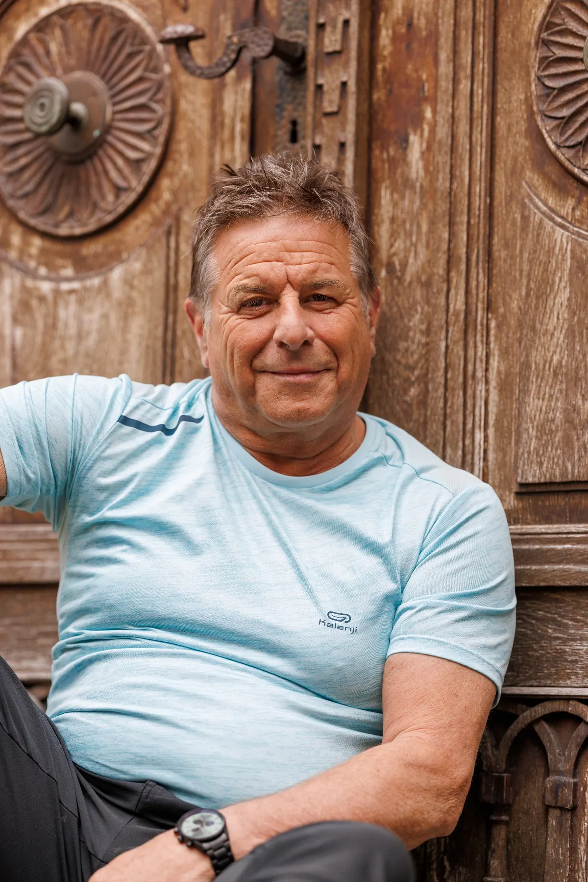Portrait von Donat, sitzend vor einer alten Holztür, ruhig in die Kamera blickend